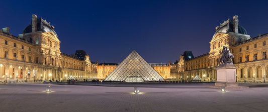 Glass pyramid and classical architecture of the Louvre Museum at night.